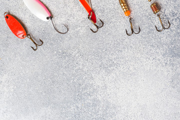 Fishing hooks and baits in a set for catching different fish on a grey background with copy space....
