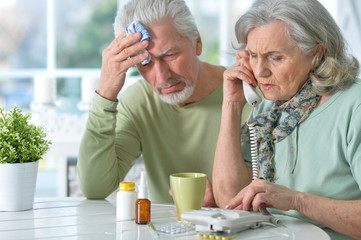 Portrait of ill senior couple with pills at home