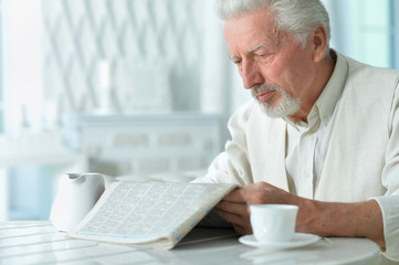 Portrait of emotional senior man reading newspaper