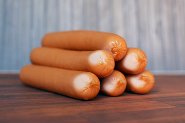 Multiple Vienna sausages piled on wooden table