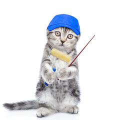 Kitten in blue cap with paint roller pointing away on empty space. isolated on white background