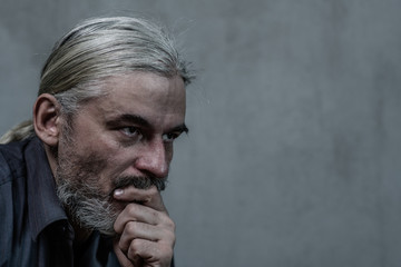 pensive senior man on dark background. Empty space for text
