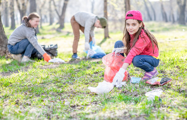 Fototapeta premium Group of a volunteers picking up trash in the park. Volunteer and ecology concept