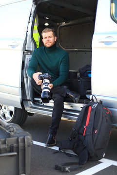 Professional photographer outside. Sit down in his van