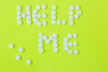 Pills in a shape of a word Help Me on a yellow background. Flat lay, top view, minimalistic style.