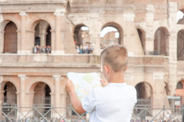 Little boy looking at tourist map in Rome in front of Colosseum, Italy. Back view, Empty space for text