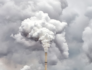 Smoke from factory pipe against dark overcast sky