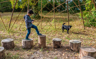Seven-year-old boy playing on wooden logs in a public park