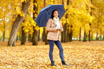 season, weather and people concept - beautiful happy young woman with umbrella in autumn park