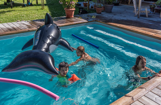 Eleven-year-old girl and two boys of  five years old and thirteen years old playing in a private swimming pool