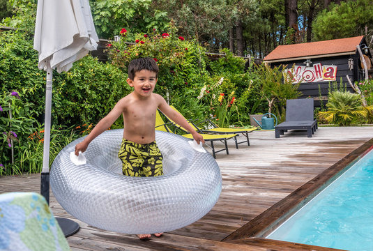 6 year old boy playing with ann inflatable float on the pool deck