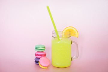 multi-colored macarons on a pink background with fresh lemon
