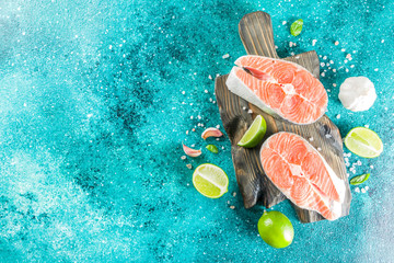Raw salmon fish steaks with spices, on marine blue concrete stone background copy space