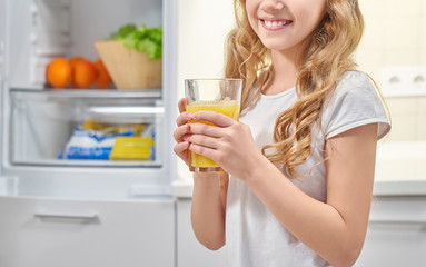 Pretty little girl keeping fresh orange juice and smiling