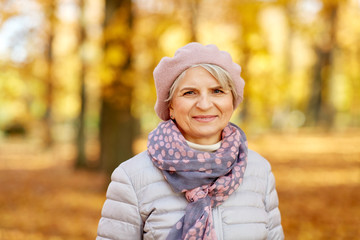 old age, retirement and season concept - portrait of happy senior woman at autumn park