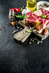 Raw ossobuco meat, beef steak with spices for cooking, black stone concrete background