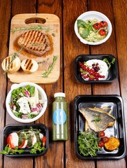 Six different dishes on a wooden table with drinks. Desserts, meat, fish, veggies and other. Top View