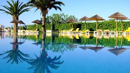 Swimming pool in beachfront tropical hotel resort with coconut palm trees landscape for beach holidays vacation, luxury destination
