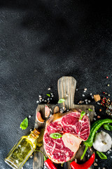 Raw ossobuco meat, beef steak with spices for cooking, black stone concrete background