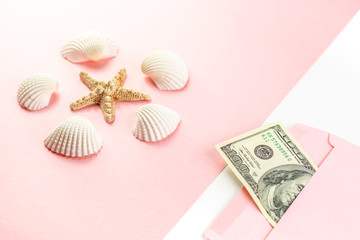 Money in a pink envelope, starfish, seashells on a blue background. Travel budget. Copy space, top view. 