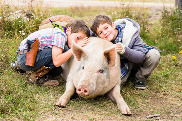 Two kids cuddling a pig, Rancho La Joya, Ranch John Wayne, Durango, Mexico, Central America