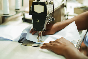closeup hands worker stitching white fabric on sewing machine