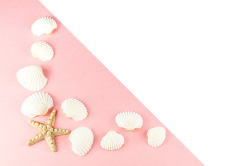 Summer tropical vacation background. Starfish surrounded by white seashells on a pink background. Copy space, top view. 