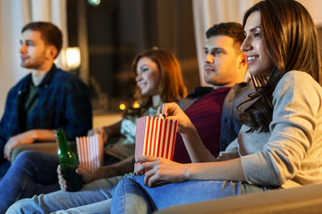 friendship and leisure concept - friends with beer and popcorn watching tv at home at night