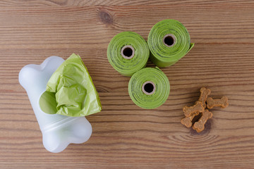 poop bags with dog treats on wooden background, flat lay
