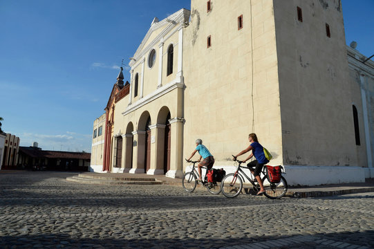 Cuba, eastern region, Bayamo,  2 cyclo tourists are riding on a paved square in front of the San Salvador church