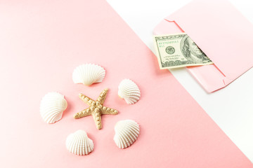 Money in a pink envelope, starfish, seashells on a blue background. Travel budget. Copy space, top view. 