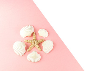 Summer tropical vacation background. Starfish surrounded by white seashells on a pink background. Copy space, top view. 