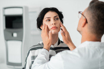 Plastic surgeon putting hands on face while examining before surgery