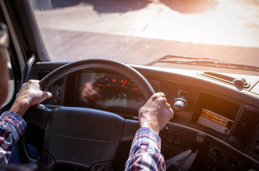 Truck driver keeps driving with one hands and change gears,The man Behind Semi Truck Steering Wheel,spot focus.