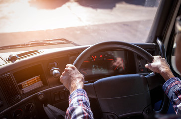 Truck driver keeps driving with one hands and change gears,The man Behind Semi Truck Steering Wheel,spot focus. © KM.Photo