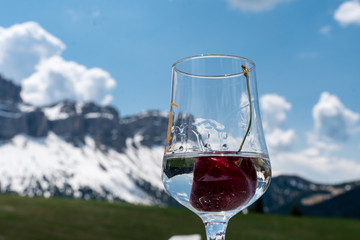 Grappa Glas mit Kirsche vor Dolomiten Bergkulisse