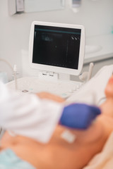 Doctor wearing white uniform making ultrasound investigation