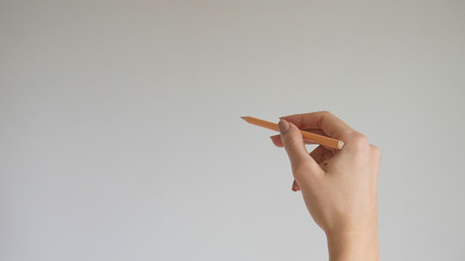  Woman's hand holding a wooden color pencil on isolated background