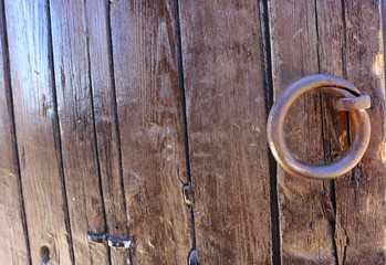 Old wooden door with aged metal door handle. Architectural textured background. Old brown wooden board background. 