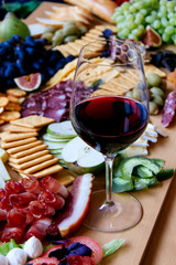 Photo of a fantastic, beautifull snacks such as fruits, cheese, olives, dried meat  for wine on a wooden table with wine glass