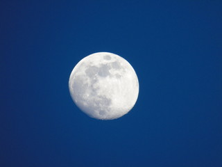 Genova, Italy - 06/15/2019: An amazing photography of the full moon over the city of Genova by night with a great clear and blue sky in the background and some stars.