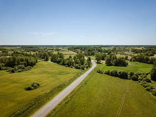 Fototapeta na wymiar country road in green forest and fields drone aerial image