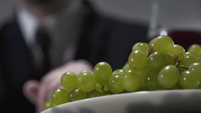 Unrecognized businessman eating grapes close-up.