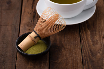tea whisk for matcha with green tea in cup on wood