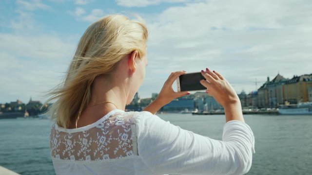 A young woman photographs a beautiful view of the city of Stockholm. Travel in sweden