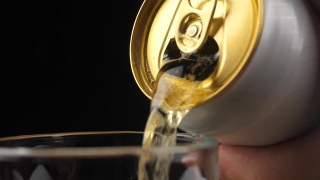 Pouring Cold Beer into a glass with water drops. Can of Beer close up.