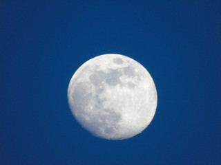 Genova, Italy - 06/15/2019: An amazing photography of the full moon over the city of Genova by night with a great clear and blue sky in the background and some stars.