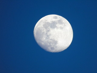 Genova, Italy - 06/15/2019: An amazing photography of the full moon over the city of Genova by night with a great clear and blue sky in the background and some stars.