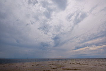 dramatic colorful clouds over sandy beach at the sea with blue sky
