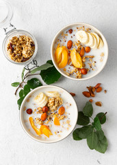 Granola cereal with fruits, nuts, milk and peanut butter in bowl on a white background. Healthy breakfast cereal top view